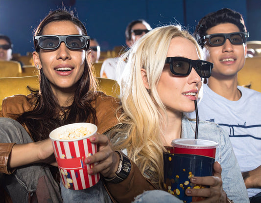 People watching a movie in a theater with popcorn and drinks.