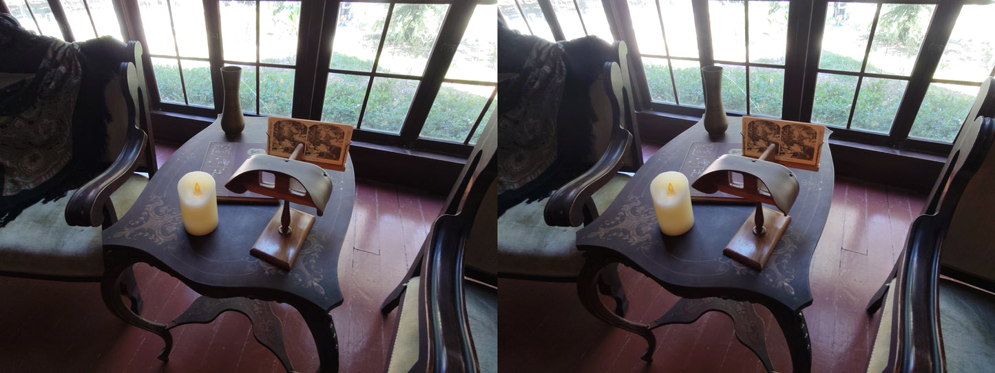 A stereoview of a living room with a table, chairs, and a stereoscope.