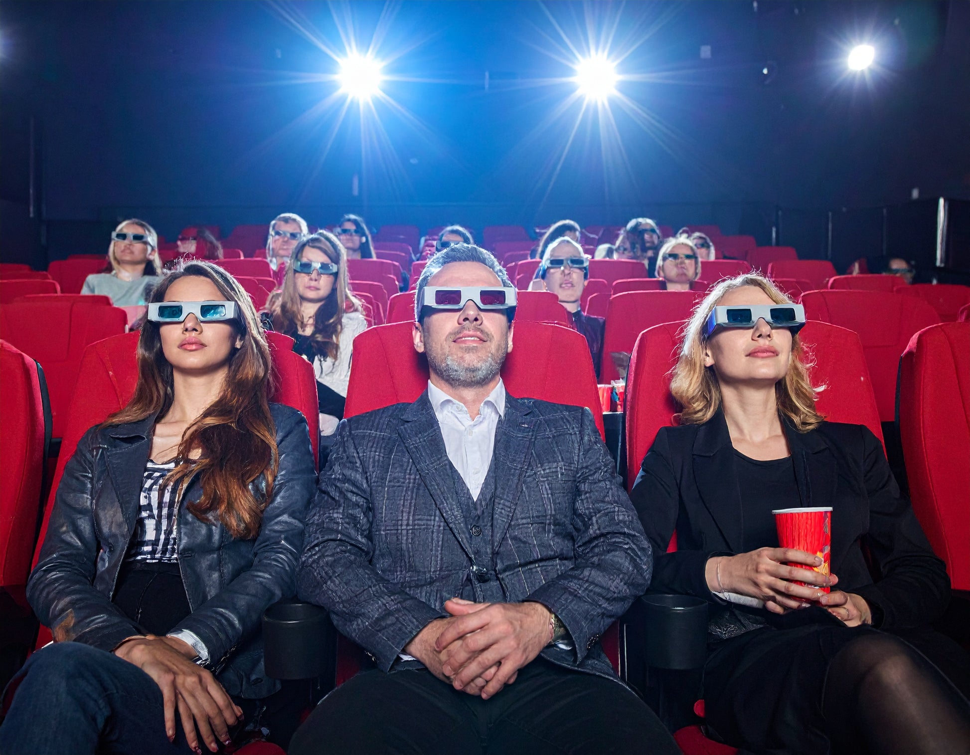 People in a movie theater wearing 3D glasses.